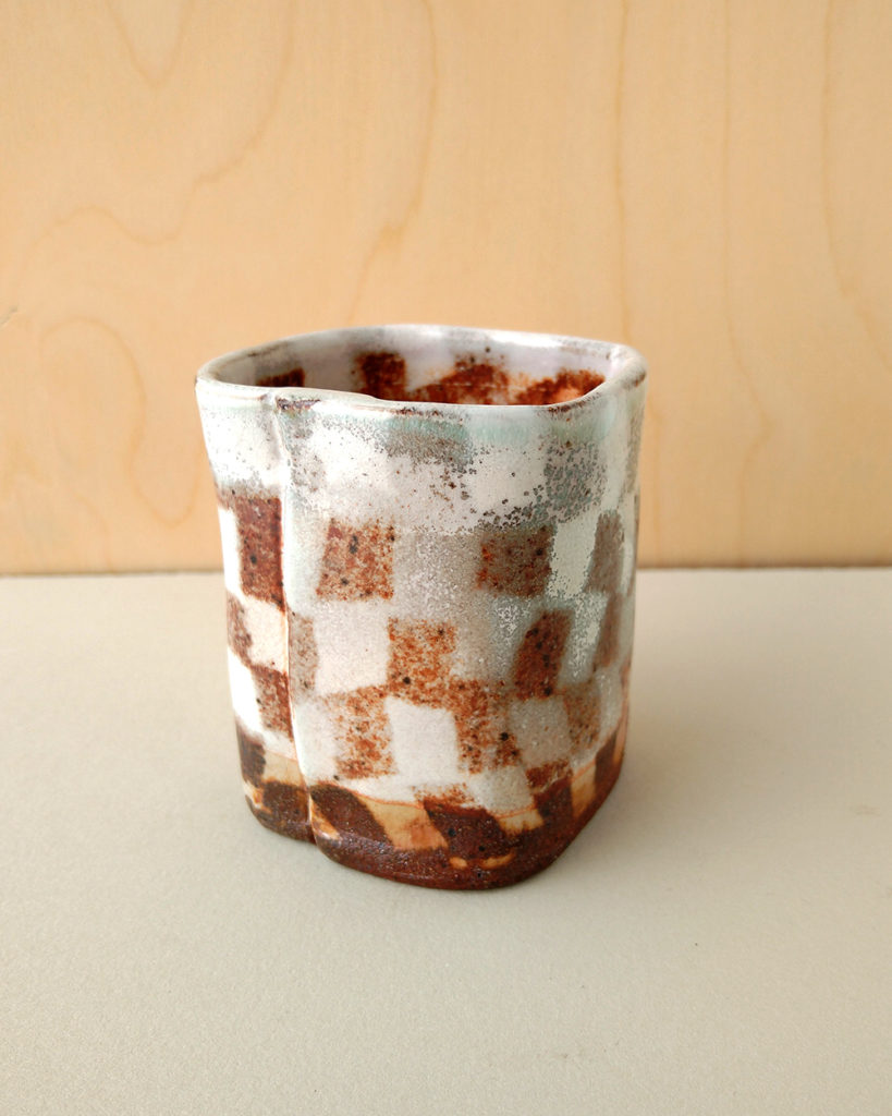 A small square tea cup with a contrasting nerikomi checker pattern.