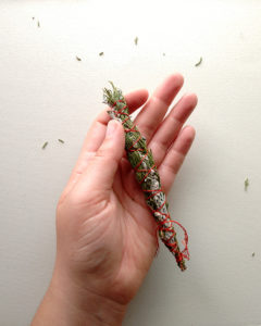A small bundle of herbs bound together with a smooth tread. This bundle is made of juniper branches and atemisia stems.