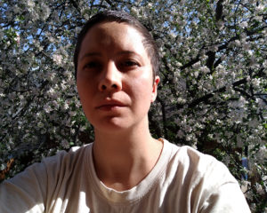 I sit in the sun in front of an enormous apple tree in full bloom