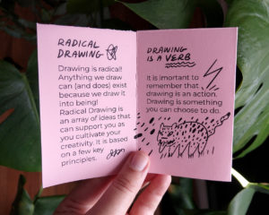 Holding the booklet open to an essay called "Radical Drawing". There are illustrations including a small jaguar and a lightning strike.